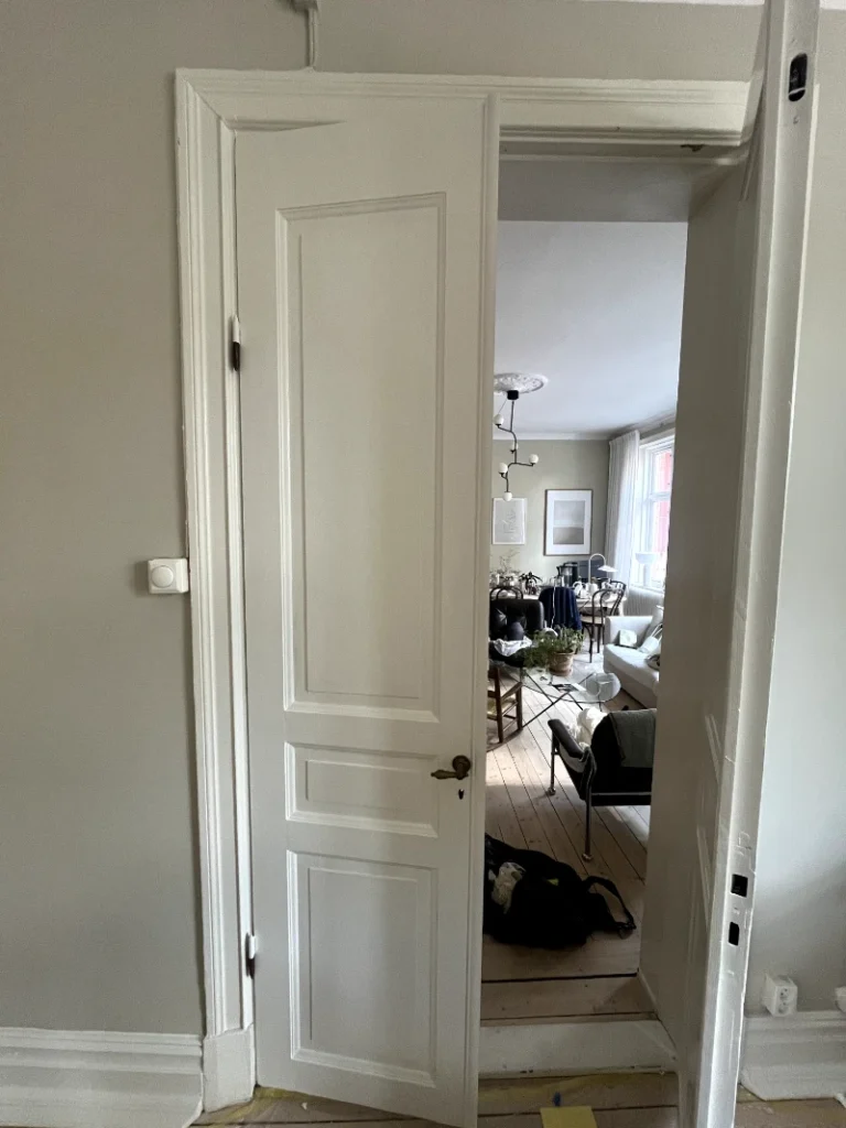 Professionell målare i Lindome applicerar blå färg på vägg med pensel, del av renoveringsprojekt.